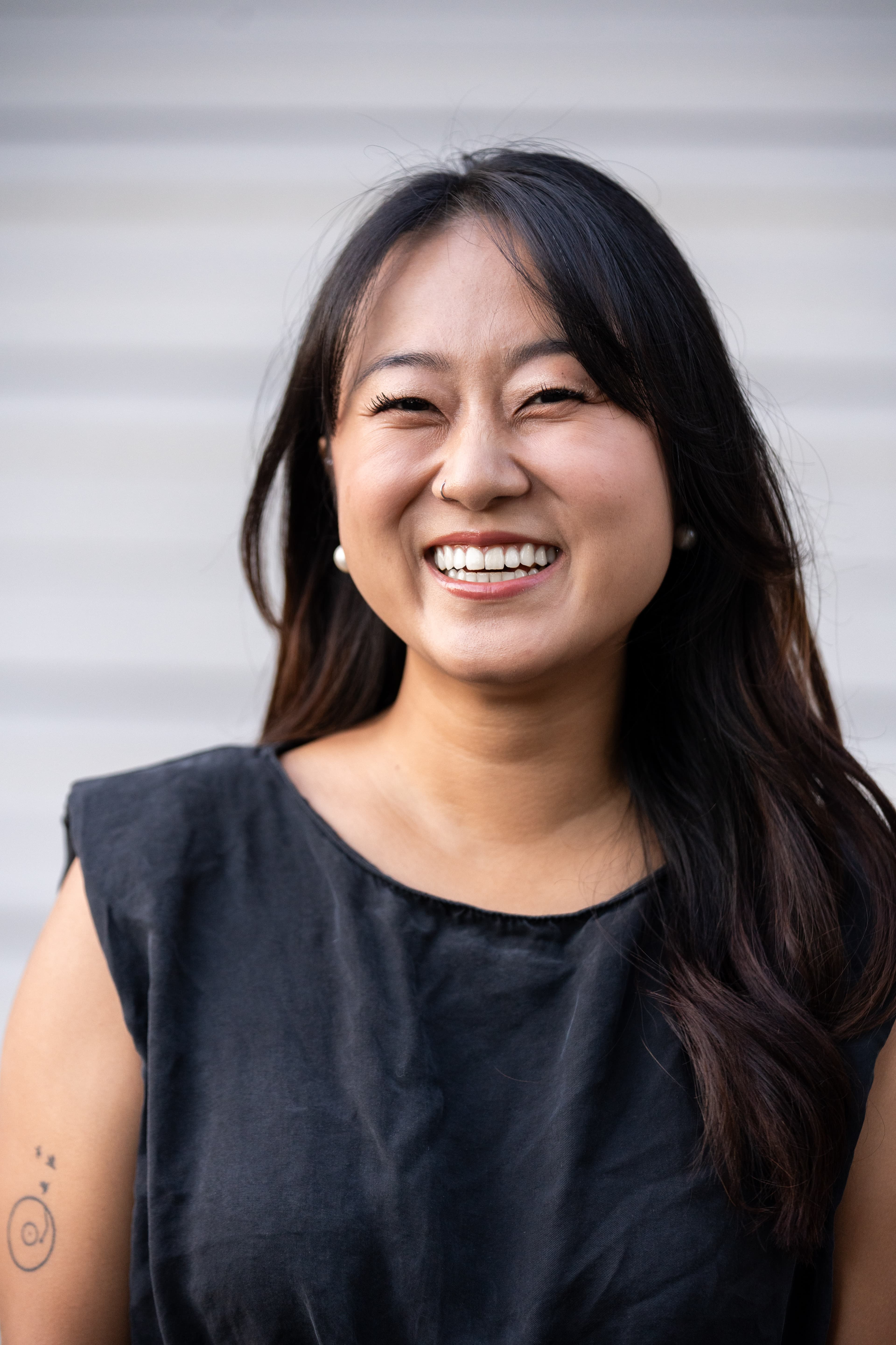 Kate Mayne smiling, seated on a wooden park bench